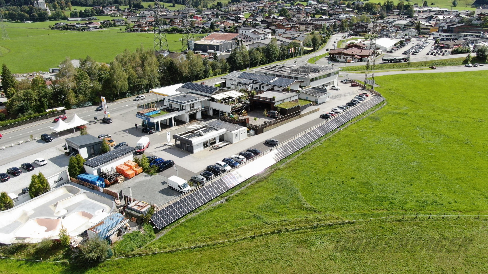 Luftaufnahme des Gewerbegebiets am Ortseingang von Kaprun, umgeben von grünen Wiesen