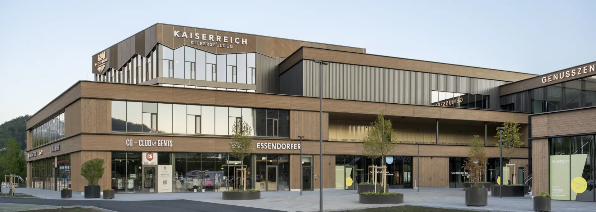Außenansicht des Kaiserreichs Kiefersfelden mit Geschäften im Erdgeschoss und Parkplätzen