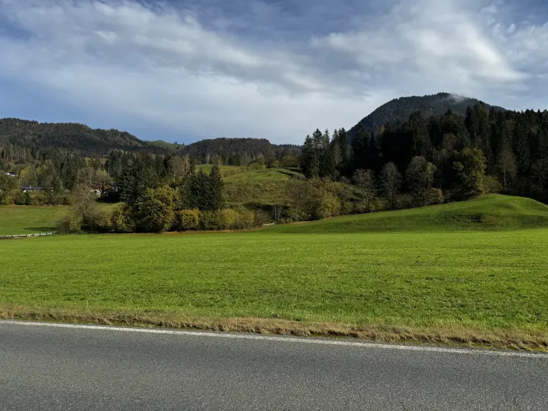 Unbebaute Freifläche des Gewerbegrundstücks im Habachpark am Straßenrand vor bewaldeter Bergkulisse